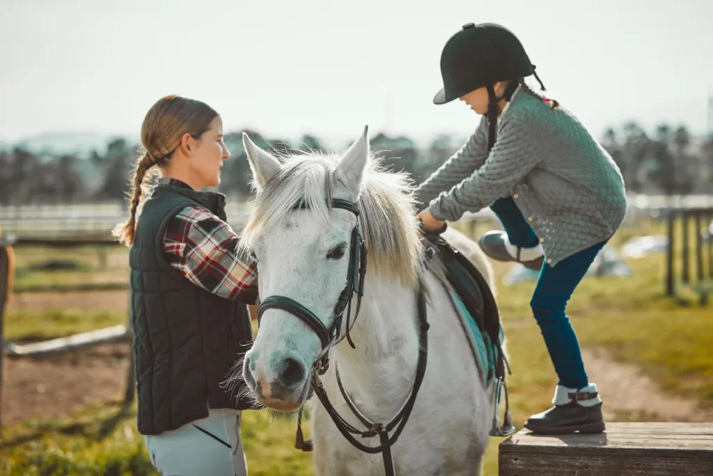 Child learning horseback riding with instructor